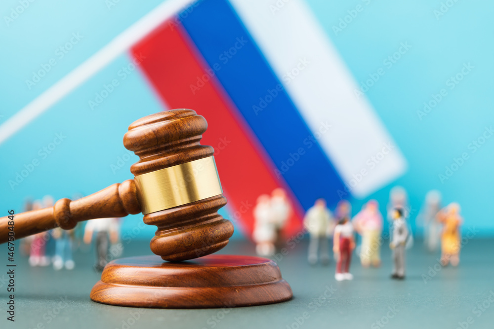 Judge gavel, against the background of a blurred flag and toy plastic men, the concept of litigation in Russian society