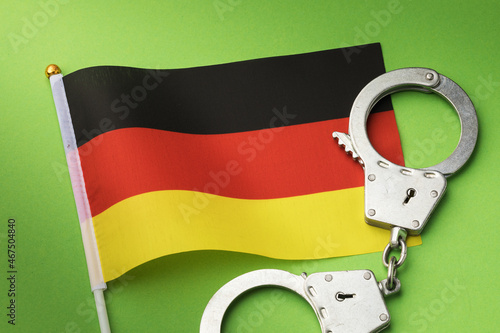 Germany flag and handcuffs on a green background, the concept of crimes in the country photo