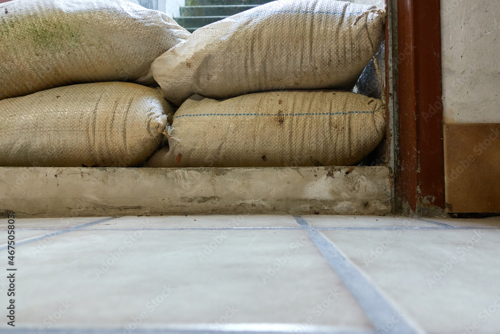 Protective measure against floods in basements. Barrier made of sandbags lies in the entrance area of a residential building. Part of. Protective measure against floods in basements. Barrier made of sandbags lies in the entrance area of a residential building. Part of.