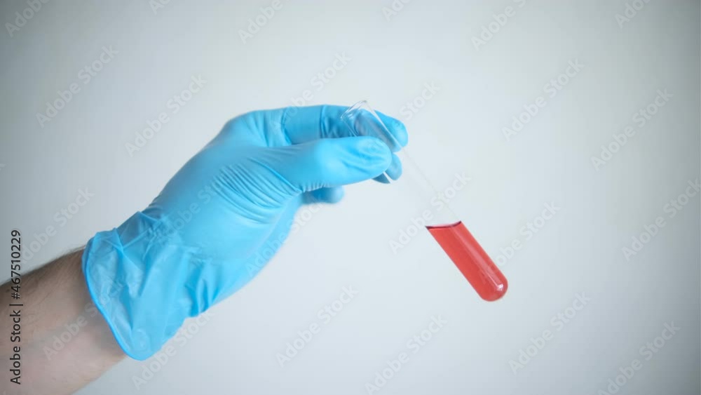 A glass tube with a red reagent, a drug analysis, which is held in the hand on a white background. Research Laboratory A glass tube with a red reagent, a drug analysis, which is held in the hand on a white background. Research Laboratory