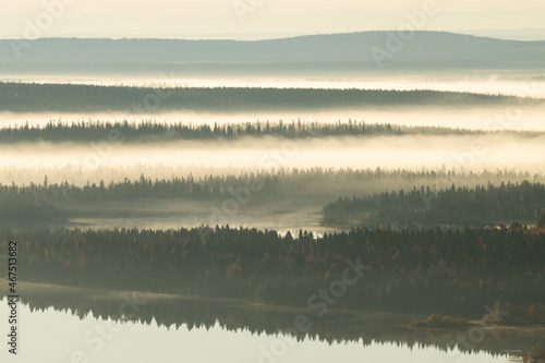 Beautiful fells in fog during a calm morning by a lake in Northern Finland near Kuusamo in autumn.