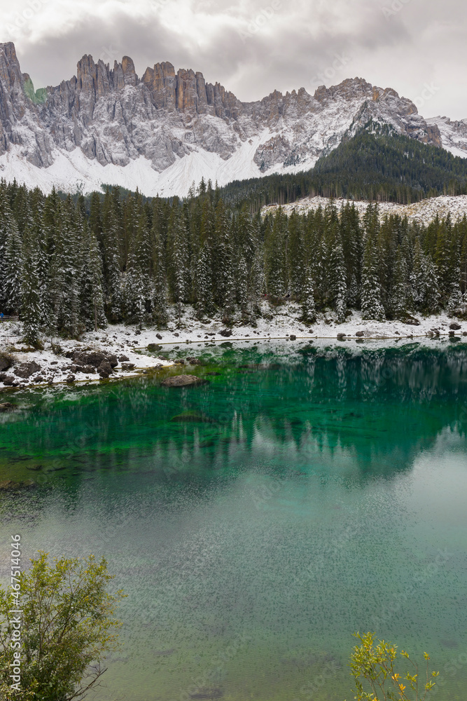 trees, mountain paths under the first snow on the lake of carezza in trentino alto adige in italy trees, mountain paths under the first snow on the lake of carezza in trentino alto adige in italy