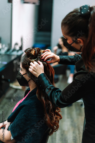 woman wearing face mask getting her hair done at local hairdresser beauty salon.