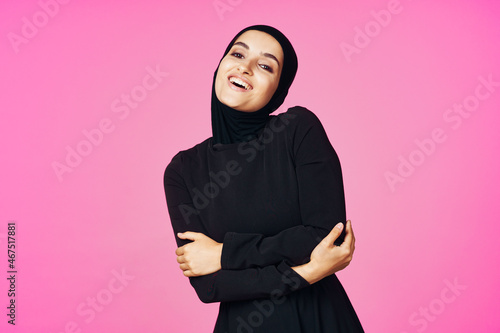 cheerful muslim woman in black hijab posing fashion pink background