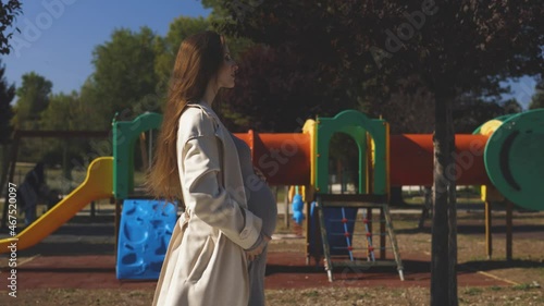 4K footage of a pregnant girl near the playground strolls in the park and imagines her baby with her
