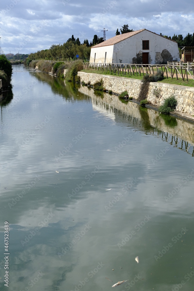 Fototapeta premium House on the canal. Farmhouse near the canal in the Cagliari lagoon.Wetland with canal. Roof with coppo tiles. Cagliari, Sardinia, Italy.
