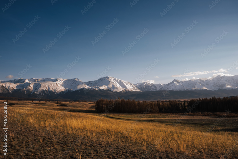 Mountain valley with peaks in the clouds and autumn forest and meadows Mountain valley with peaks in the clouds and autumn forest and meadows