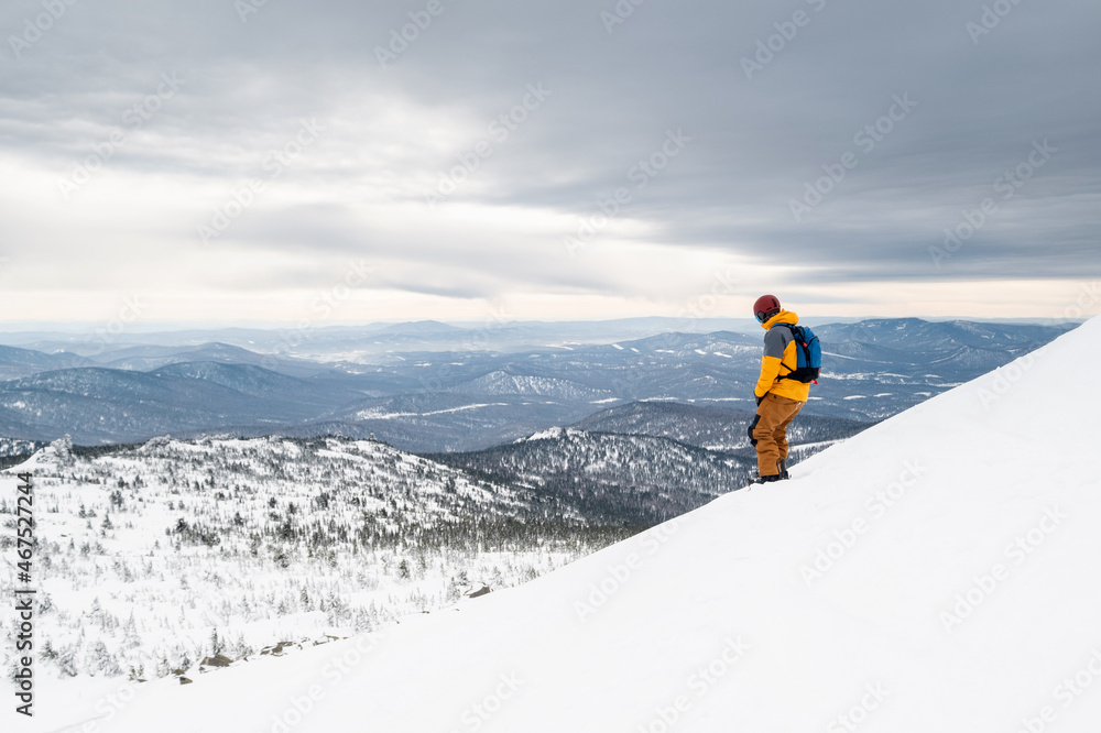 Snowboarder riding on snow cowered slop on snowboard. Mountain skyline on background, winter holiday in ski resort