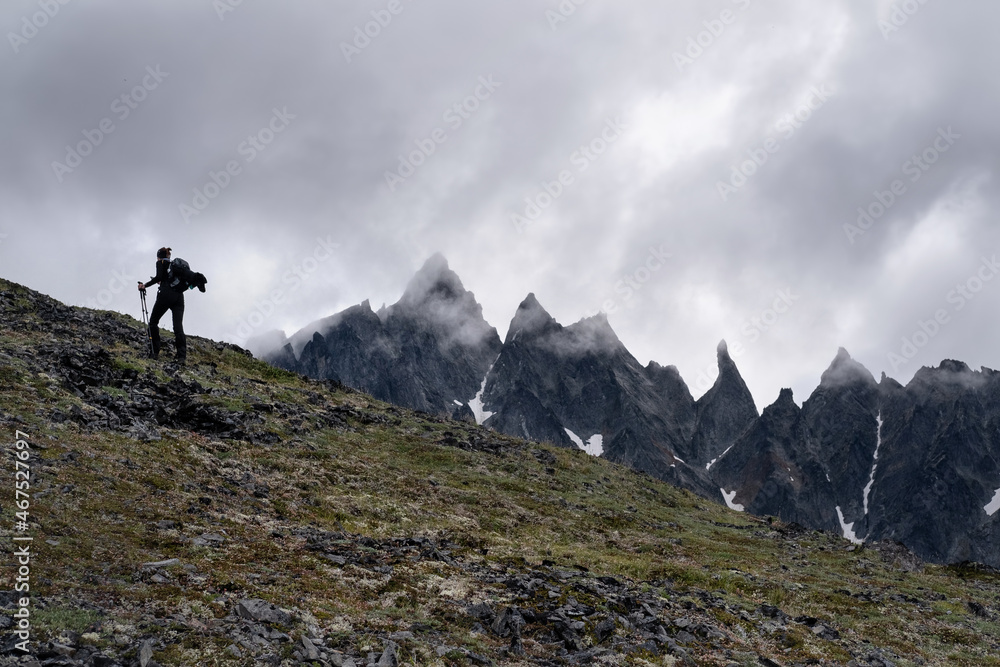 Silhouette of hiker female walking in the mountains. Climbing peak, trekking in Kamchatka