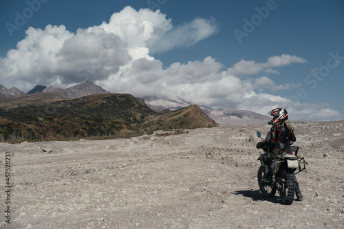 Woman motorcyclist in area of active volcano Shiveluch.  Dry river desert. Post-apocalyptic landscape  Kamchatka