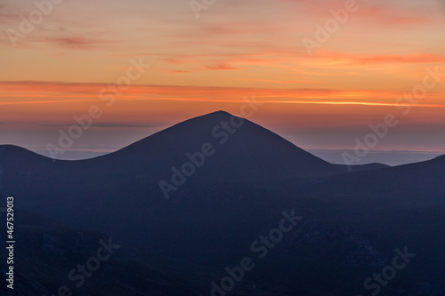 Watching the Sunrise on Slieve Binnian during summer, looking towards Slieve Donard, Mourne mountains, County Down. Northern Ireland