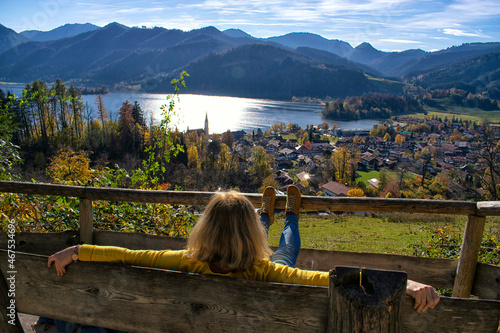 Woman watching at a beautiful mountain landscape . 
A middle aged Woman contemplates a landscape of Schliersee lake in the german Alps during Autumn, Bavaria, Germany