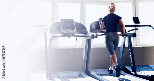 Back view of sports single woman running on treadmill.