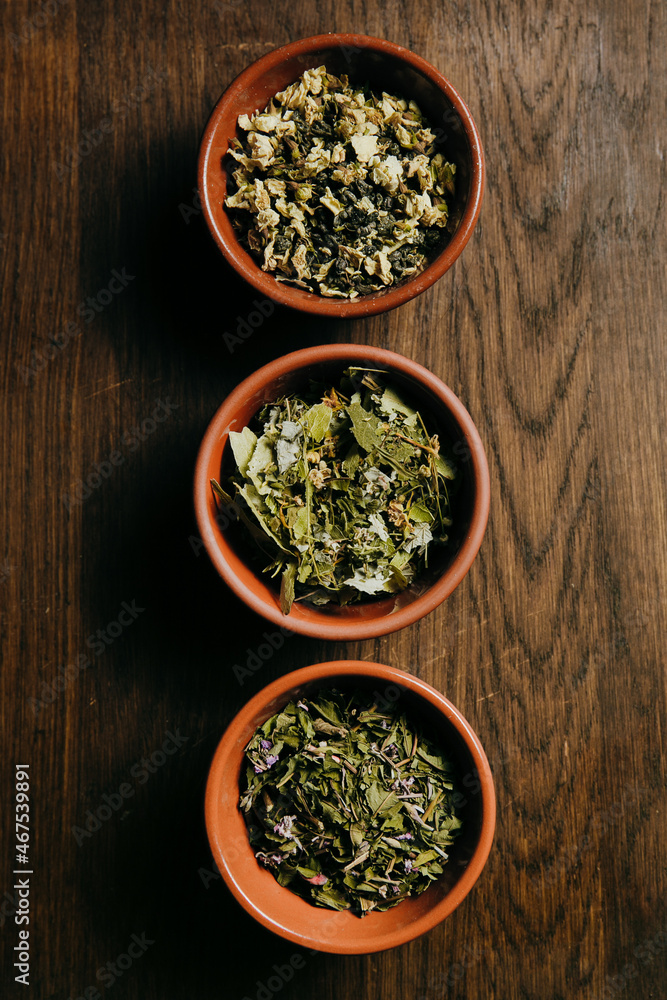 Close up of assortment of dry tea in brown ceramic bowls on a wooden board. Tea ceremony concept Close up of assortment of dry tea in brown ceramic bowls on a wooden board. Tea ceremony concept