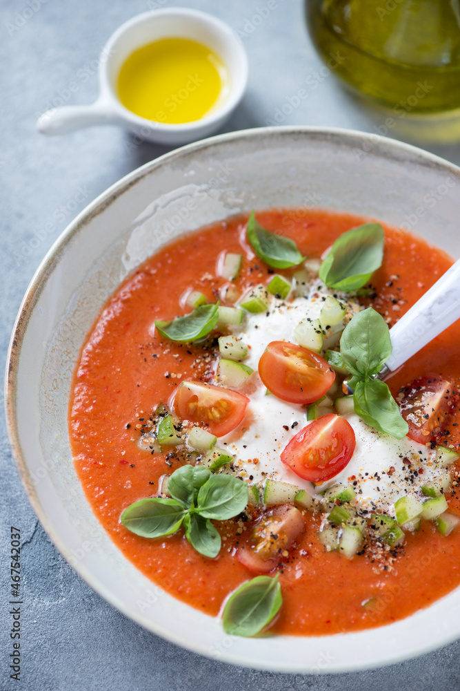 Cold gazpacho soup made of red tomatoes and served with burrata cheese and green basil, close-up, vertical shot Cold gazpacho soup made of red tomatoes and served with burrata cheese and green basil, close-up, vertical shot