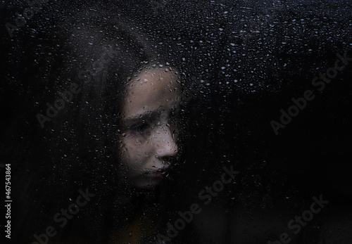 portrait of a girl with a reflection on a dark background by the window