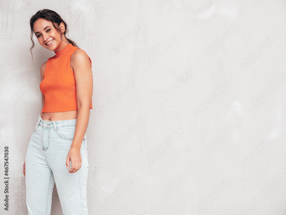 Young beautiful smiling female in trendy summer clothes. Sexy carefree woman posing near grey wall in studio. Positive brunette model having fun and going crazy. Cheerful and happy Young beautiful smiling female in trendy summer clothes. Sexy carefree woman posing near grey wall in studio. Positive brunette model having fun and going crazy. Cheerful and happy