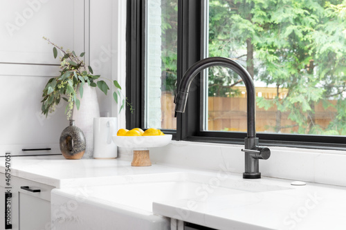 Canvas Print Kitchen sink detail shot in a modern, renovated kitchen with black window frames, a dark faucet, white cabinets, farmhouse sink, and cozy decor