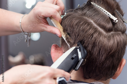Hairdresser uses hair clipper for fringing hair, horizontal closeup