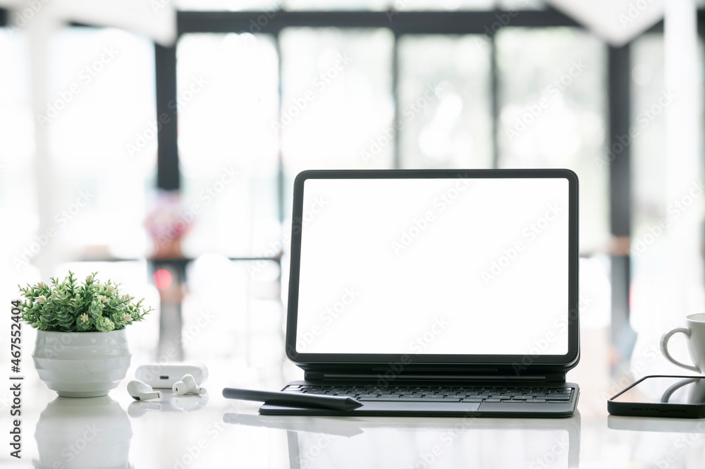 blank white screen tablet with magic keyboard on wooden table.