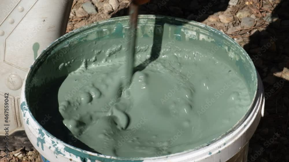 Stirring mixing water base paint in a bucket . Slow motion Stirring mixing water base paint in a bucket . Slow motion