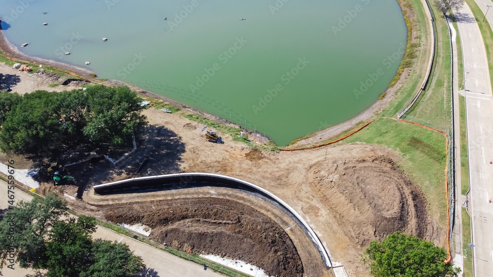 Top view residential pond renovation with construction machines and safety barrier fence at Rheudasil Park, Flower Mound, TX