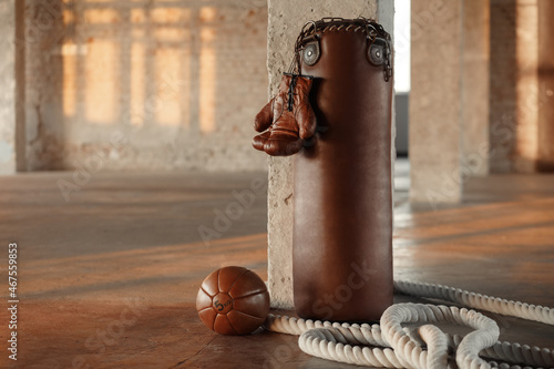 Punching bag with gloves brown leather in gym. Vintage sports equipment photo