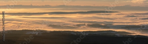 Foggy valley with cloud rolling over the hills at sunrise in winter. Panorama.