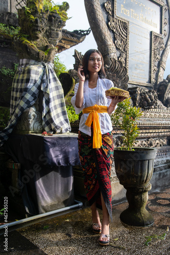 Young local Girl in a Balinese temple carrying offerings, Bali, Indonesia.