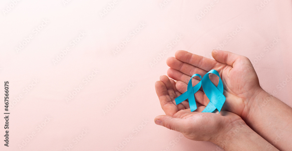 Man holding two Blue Ribbons for supporting people living and illness with prostate cancer and achalasia and adrenocortical carcinoma, male health care concept Man holding two Blue Ribbons for supporting people living and illness with prostate cancer and achalasia and adrenocortical carcinoma, male health care concept