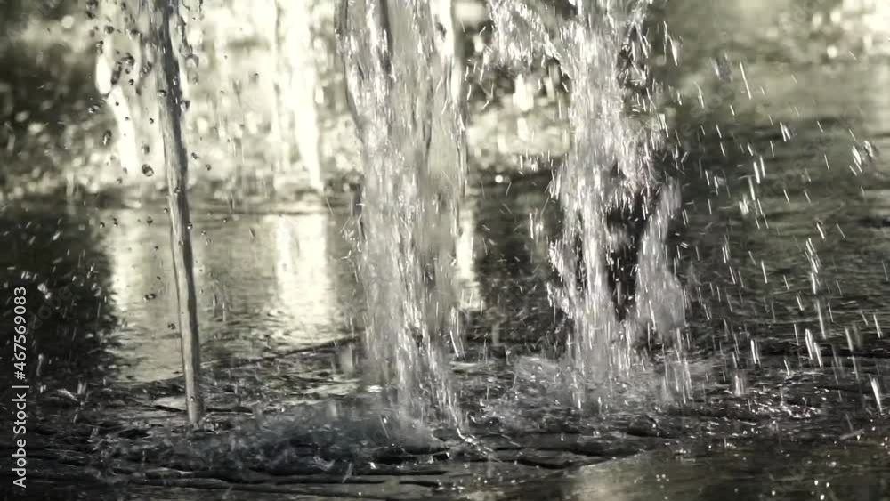 Water jets from the city fountain in the park in the sunset sunlight. Water pressure and pressure. Splashing water. Slow motion. Close up Water jets from the city fountain in the park in the sunset sunlight. Water pressure and pressure. Splashing water. Slow motion. Close up
