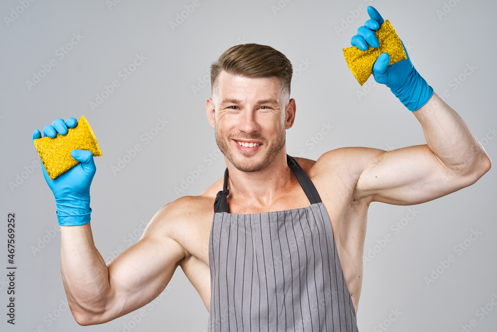 a man in an apron wearing rubber gloves washing dishes a man in an apron wearing rubber gloves washing dishes