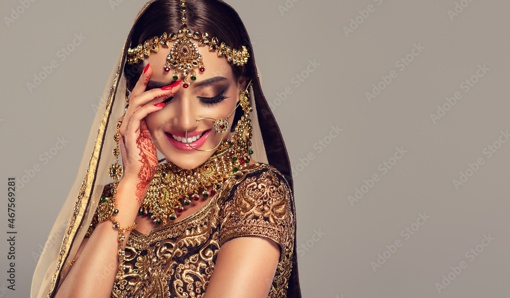 Portrait of beautiful indian girl. Young hindu woman model with golden kundan jewelry set, earrings, tikka and bracelet  . Traditional India costume lehenga choli or saree .  - obrazy, fototapety, plakaty 