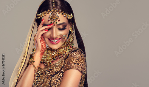 Portrait of beautiful indian girl. Young hindu woman model with golden kundan jewelry set, earrings, tikka and bracelet  . Traditional India costume lehenga choli or saree .  photo