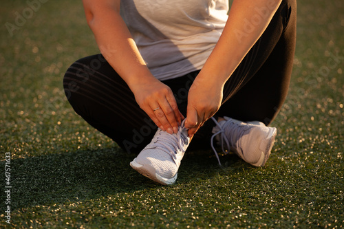 Athletic girl tying the laces of sneakers at the stadium