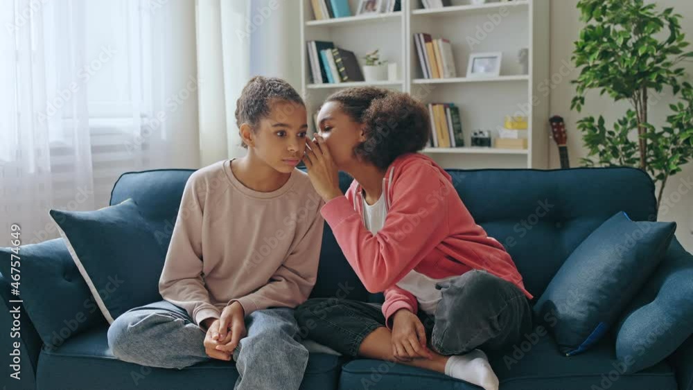 Black teenage girl telling bad news to best friend at home, whispering secret Black teenage girl telling bad news to best friend at home, whispering secret