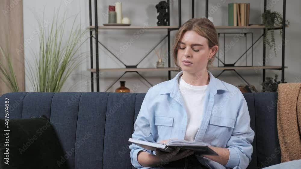 Young pretty woman reading book in cozy living room thinking, learning, studying, education, read books, stay home concept. Young pretty woman reading book in cozy living room thinking, learning, studying, education, read books, stay home concept.