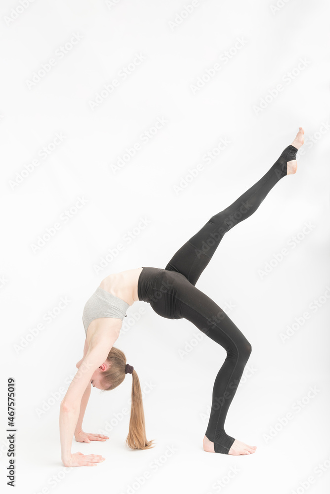 Urdhva Dhanurasana. Upward Bow Wheel Pose. Girl is engaged in gymnastics on white background. Yoga practice. Performing asanas.