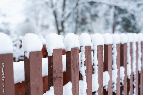 Snow cover. Winter weather. Garden under snow. Close-up of wooden fence covered in snow during winter season.