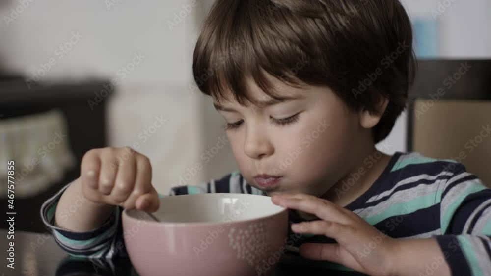 Child Eat Cornflakes with Milk. Little Hungry Boy Eating Breakfast Corn Cereal From Plate Sitting Home at Table in Kitchen. Healthy Nutrition Flakes. Portrait of Kid Eating Eating Muesli for Breakfast Child Eat Cornflakes with Milk. Little Hungry Boy Eating Breakfast Corn Cereal From Plate Sitting Home at Table in Kitchen. Healthy Nutrition Flakes. Portrait of Kid Eating Eating Muesli for Breakfast