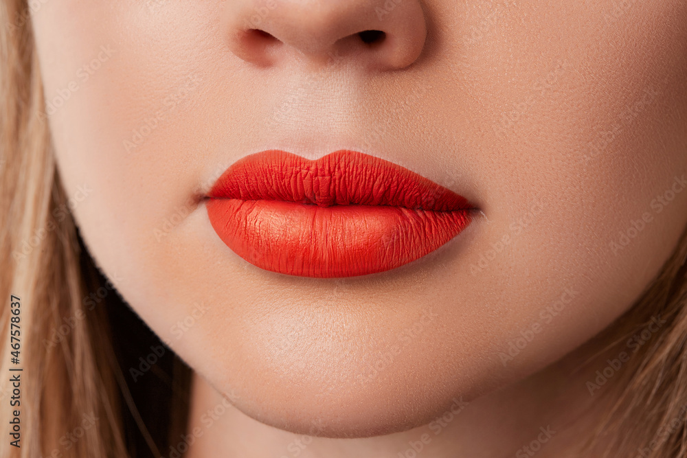 Fototapeta premium Close up macro female plump lips with red matte lipstick. Beauty fashion portrait personal care and make up