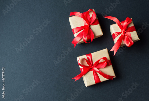 Festive concept - gifts with craft paper with a red bow on a black background. composition for christmas, new year and holidays. flat lay with place for text. 
