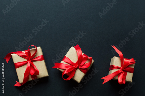 Festive concept - gifts with craft paper with a red bow on a black background. composition for christmas, new year and holidays. flat lay with place for text. 