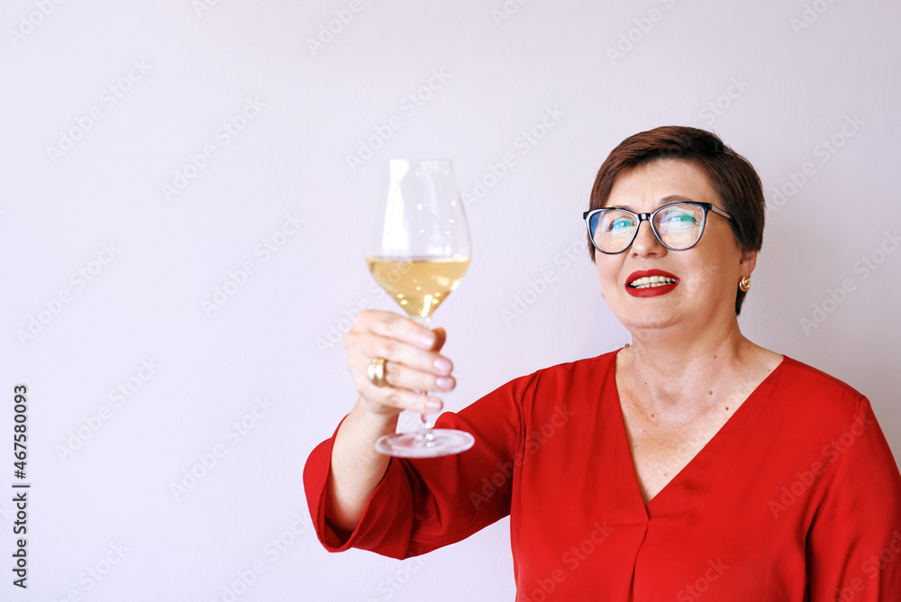 stylish mature senior woman in red blouse with glass of white wine celebrating new year. Fun, party, style, lifestyle, alcohol, celebration concept stylish mature senior woman in red blouse with glass of white wine celebrating new year. Fun, party, style, lifestyle, alcohol, celebration concept