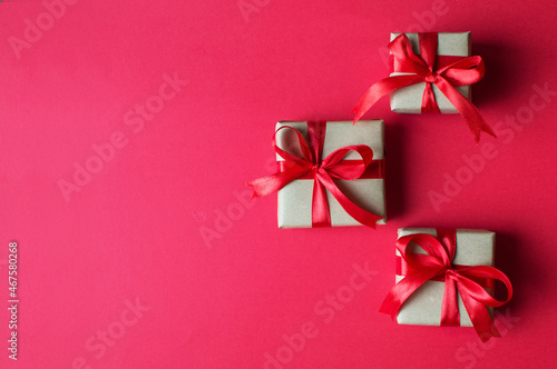 Festive concept - gifts with craft paper with a red bow on a red background. composition for christmas  new year and holidays. flat lay with place for text. 