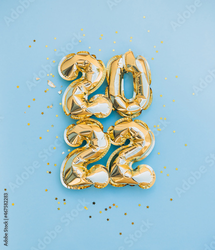 Happy New year and christmas holiday concept 2022. Gold balloons with glitter stars on blue background. Gift card. Top horizontal view