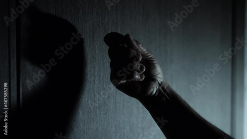 A knock on a door in the dark, a woman knocks on a wooden door. photo