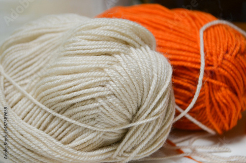 A light, horizontal photo of orange and white natural yarn on the table.