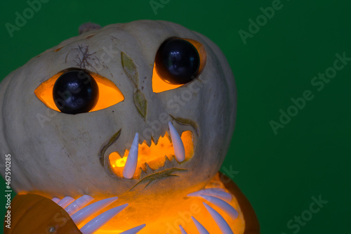 alien pumpkin with black eyes and shark teeth with green background detail