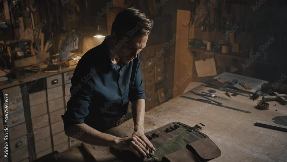 Handmade craft accessories. Professional man tailor finishing leather case for tools at his creative workshop Handmade craft accessories. Professional man tailor finishing leather case for tools at his creative workshop